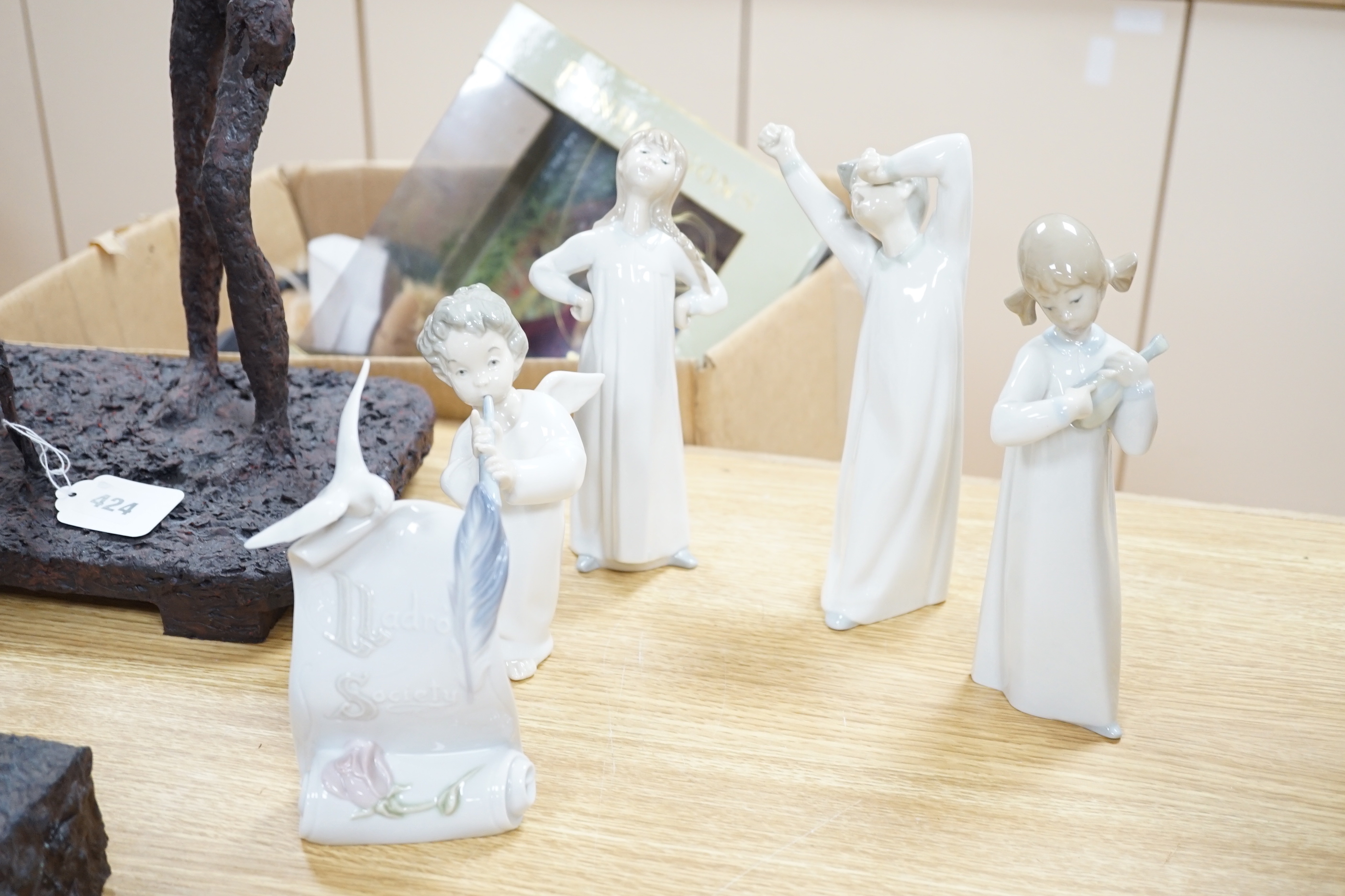A Lladro circular wooden plaque with three angelic faces, four models of children, an angel, female figure in a hat another and glazed plaque (9) tallest 32cm high